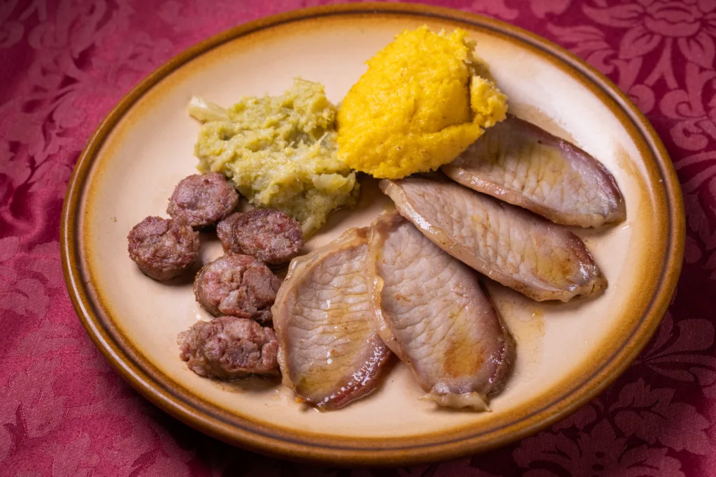 Klobase, zrezki, polenta in zelje na krožniku